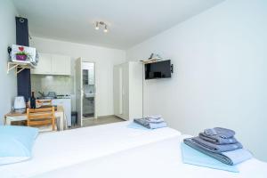 een witte slaapkamer met 2 bedden en een keuken bij Apartments Green Garden in Dubrovnik