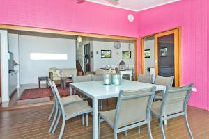 uma sala de jantar com paredes cor-de-rosa, uma mesa e cadeiras em Moreton View @ Tangalooma em Tangalooma
