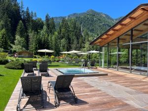 une terrasse avec une table, des chaises et une piscine dans l'établissement Hotel Arnaria, à Ortisei