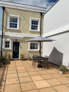 a patio with a table and an umbrella in front of a house at Solent Haven, Lymington with sea views and parking in Lymington