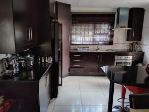 a kitchen with brown cabinets and a black counter top at Cheerful Family Holiday Home in Brakpan
