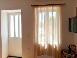 a window with a curtain next to a door at Lemon Garden 1 in Karídhion