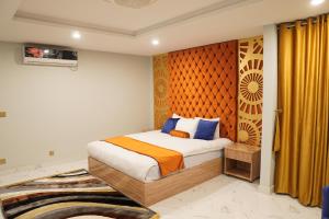 a bedroom with a bed with an orange and blue blanket at NuvaHotel in Islamabad