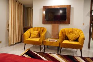 two yellow chairs and a tv in a living room at Nuva Hotel-DHA 2 in Islamabad