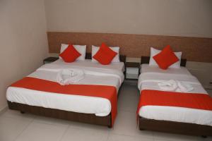 2 camas en una habitación con almohadas rojas y blancas en Hotel Nawanagar Residency, en Jamnagar