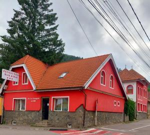 a red house with a red roof on a street at Pensiunea Rock and Red in Râşnov