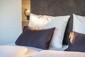 a bed with white pillows on top of it at Luisl Hof - Apartment Pomum in Cornaiano