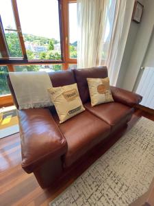 a brown leather couch with pillows in a living room at ARTZA ETXIE LA CASA EBI01934 in Bermeo