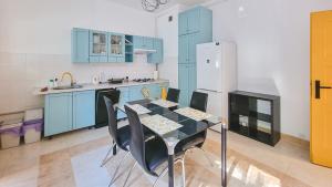 a kitchen with blue cabinets and a table and a refrigerator at Pokoje Rybnicka 10 in Katowice