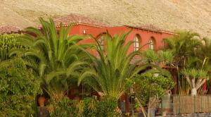 een rood gebouw met palmbomen ervoor bij Finca Eva-Adults 0nly in La Playa Calera
