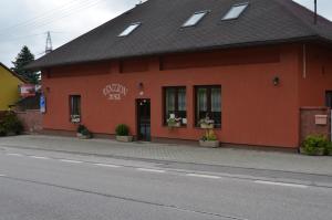 ein rotes Gebäude am Straßenrand in der Unterkunft Penzion Aura in Dvůr Králové nad Labem