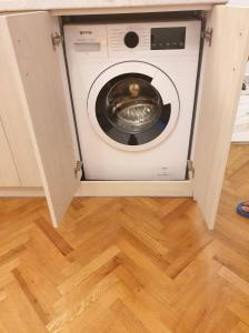 a washing machine in a kitchen with a wooden floor at Апартамент BOHO CHIC Free parking in Varna City