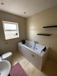 a bathroom with a tub and a toilet and a sink at Town villa with charming garden, bbq area & Sleeps 6 in Cashel +23 photos