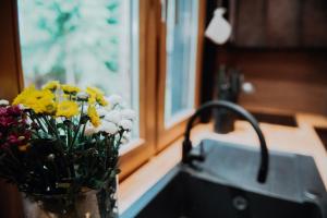 a sink with a vase of flowers next to a window at Dom Królowy Most 67 in Królowy Most