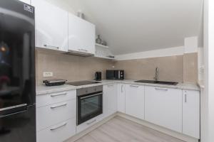 La cuisine est équipée de placards blancs et d'un réfrigérateur noir. dans l'établissement Apartment Gloria, à Dubrovnik