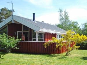 a man standing on the porch of a red house at Unique Seaside Holiday Home in Hadsund near Terrace in Øster Hurup