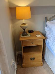 a lamp on a night stand next to a bed at Clover Cottage - Delightful 1-bed cottage in the heart of Ambleside in Ambleside