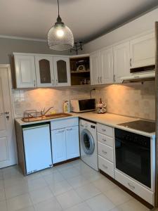 uma cozinha com armários brancos e uma máquina de lavar e secar roupa em Анси em Pomorie