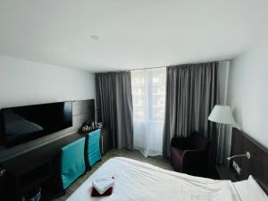 a hotel room with a bed and a flat screen tv at 4* Boutique Zimmer am Düsseldorf Hafen + ÖPNV & TG in Düsseldorf