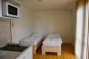 ŽluticeにあるAutokemp Žluticeのベッド2台、電子レンジが備わる小さな客室です。
