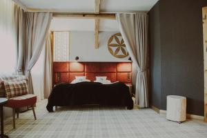 um quarto com uma cama preta e uma cadeira em Bajka Hotel & Resort em Grodziec