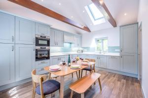 a kitchen with white cabinets and a wooden table and chairs at Ferry Corner Cottage, Sudbourne in Woodbridge