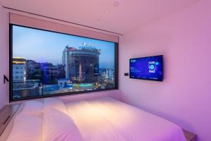 a bedroom with a large window with a tv at SOJO Hotel Ha Long in Ha Long