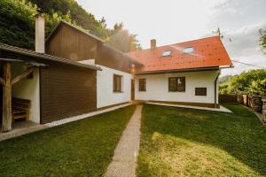 a house with a red roof and a grass yard at Na Želivce chalupa Marie in Želiv