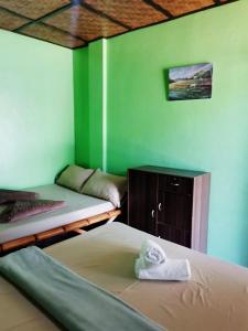 um quarto com 2 beliches num quarto com paredes verdes em In-N-Out Hostel em Siquijor
