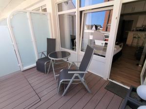 a balcony with a table and a chair and a glass door at Alte Teestube Alte Teestube 57 in Norderney +3 photos