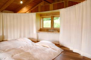 Cama blanca en habitación con ventana en HAKU 100-year-old Quaint Japanese Style Villa en Takayama