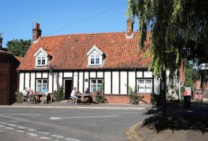 pessoas sentadas em mesas fora de um edifício em The Queens Head Glamping em Foulsham