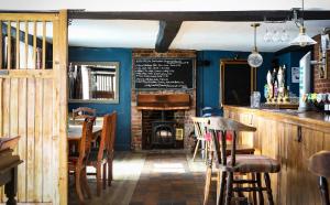 un pub con chimenea, mesa y sillas en The Queens Head Glamping, en Foulsham