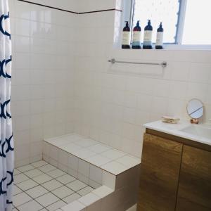 a bathroom with a shower with a sink and bottles of wine at Sandy toes in Yeppoon