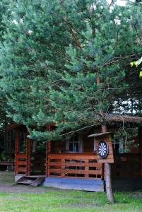 una cabaña de madera con un árbol delante en Laumių Nameliai en Anykščiai