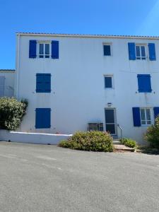 a white building with blue windows and a street at Appartement vue mer in La Guérinière