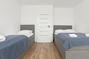 a bedroom with two beds and a door at Lake House Sosnowy Las Mielno by Renters in Mielno