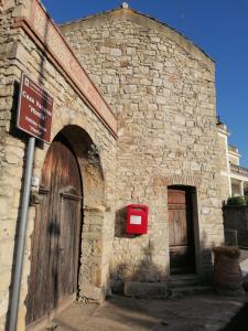 un viejo edificio de piedra con una caja de correo rojo. en Domus de Jara - Casa Montis en Baradili