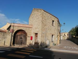un antiguo edificio de piedra con una puerta en una calle en Domus de Jara - Casa Montis en Baradili
