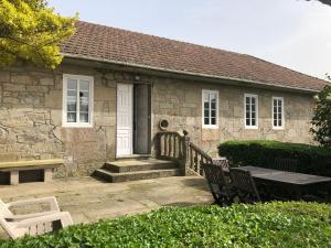 ein Steinhaus mit einem Tisch und Bänken davor in der Unterkunft Casa de Alicia Pontevedra Moraña Rías Baixas Casa Entera VT-PO-OOOO32 in Moraña