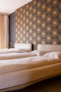 1 Schlafzimmer mit 3 Betten und einer tapezierten Wand in der Unterkunft Rotonda in Gordola
