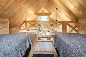 two beds in a room with a wooden ceiling at Bieszczadzka Łąka in Kalnica