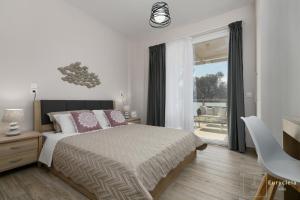 a white bedroom with a bed and a balcony at Villa Eurycleia - AKTI homes in Pitsidia