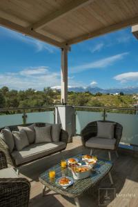 eine Terrasse mit einem Sofa und einem Tisch mit Essen drauf in der Unterkunft Villa Eurycleia - AKTI homes in Pitsidia