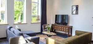 sala de estar con sofás y TV de pantalla plana. en Spoorzicht Long Stay Apartments, en Loppersum
