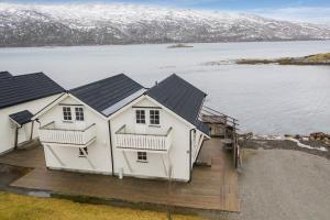 a large white house with a deck next to a body of water at Idyllisk sjøhus på Naurstad in Bodø