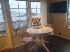 a table with flowers and vases on it in a room with windows at Idyllisk sjøhus på Naurstad in Bodø