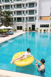 Zwei Frauen sind auf einem aufblasbaren Floß in einem Schwimmbad in der Unterkunft Himawari Hotel Apartments in Phnom Penh