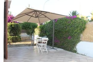 un patio con una mesa y una sombrilla en San Leone Home, en San Leone
