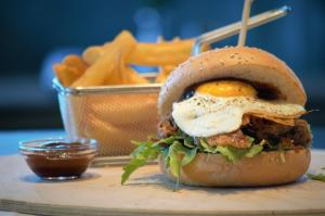 a sandwich with an egg on top and a basket of fries at Hotel Das Zeit in Lenzing